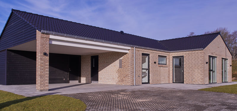 Moderne hus med sort tegltag, integreret carport og overdækket indgang – inspiration til nybyggeri og egne husdrømme.