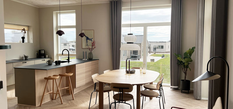 Lyst køkken-alrum fra eurodan-huse med køkkenø i træ, spiseplads, sildebensgulv, ovenlys og høje vinduespartier, der giver inspiration til moderne husdrømme.