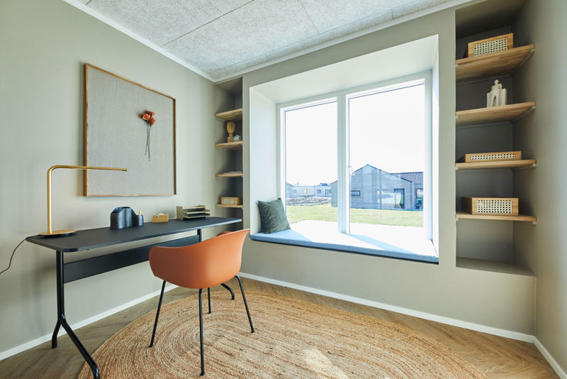Lyst hjemmekontor i moderne vinkelhus med skrivebord, indbyggede hylder og bred vindueskarm med siddeplads – inspiration til funktionel indretning i nybyg og drømmehuset.