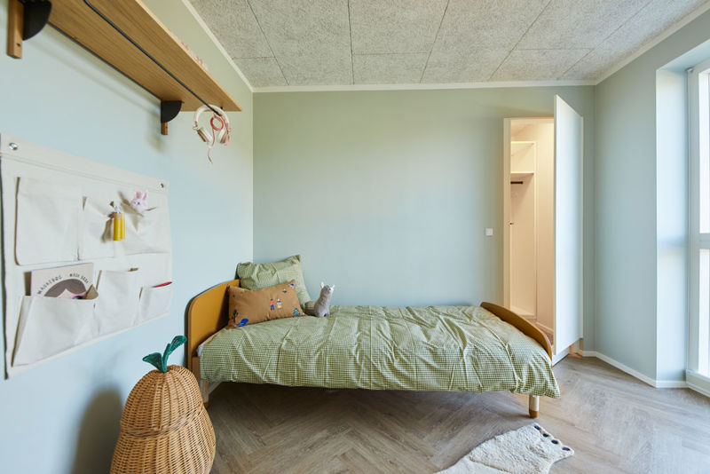 Hyggeligt børneværelse i moderne vinkelhus med enkeltseng, lysegrønne vægge, vægopbevaring og adgang til garderobe – inspiration til indretning af nybyg og drømmehuset.