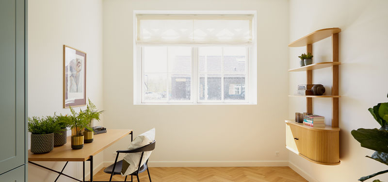 Lyst kontor eller værelse fra eurodan-huse med skrivebord langs væggen, hvid kontorstol, stort sprosset vindue, væghængt reol i lyst træ, grønne planter og sildebensgulv – inspiration til hjemmekontor i nybyggeri og husdrømme med fleksible rum.