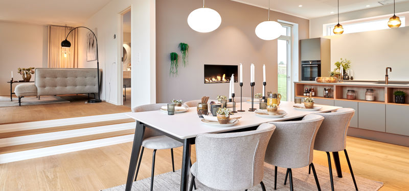 Lyst køkken-alrum med spiseplads, indbygget pejs og niveauforskel til stuen – moderne indretning i et nyt eurodan-hus.