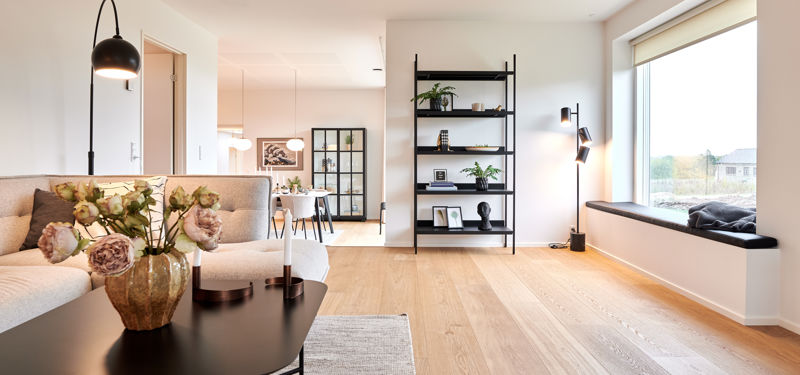 Lys stue i nybygget udstillingshus fra eurodan-huse med sansevindue, sofa og åben forbindelse til spiseplads for familiens husdrømme