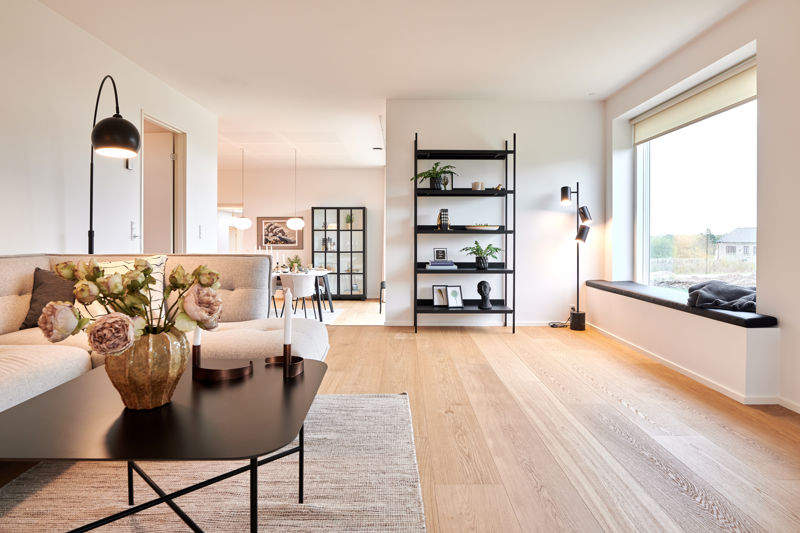 Lys stue i nybygget udstillingshus fra eurodan-huse med sansevindue, sofa og åben forbindelse til spiseplads for familiens husdrømme