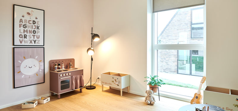Børneværelse i nybygget udstillingshus fra eurodan-huse med legekøkken, plakater og stort vindue som inspiration til familiens husdrømme