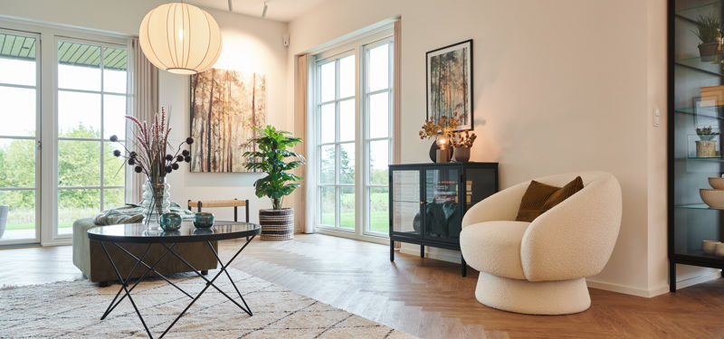 Lyst køkken-alrum fra eurodan-huse med store vinduespartier mod haven, spisebord, køkkenø, lyse gardiner og bred åbning ud mod terrasse – inspiration til nybyggeri, husbyggeri og husdrømme med fokus på dagslys og åbne rum.