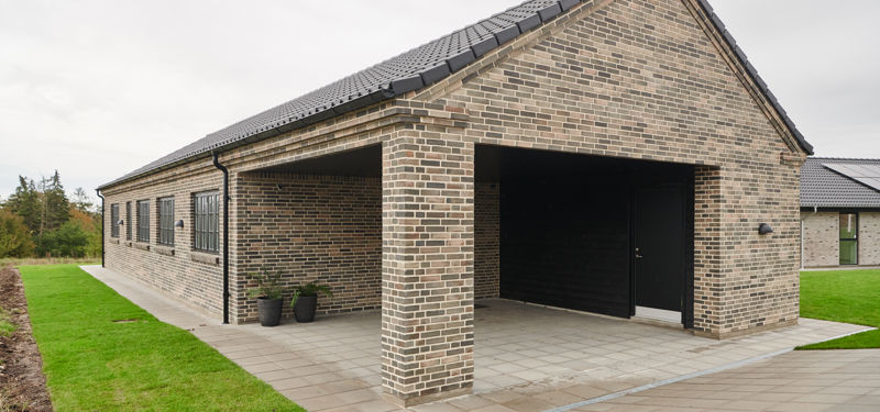 Moderne murstenshus med saddeltag, integreret garage og overdækket indgangsparti – inspiration til nybyggeri og et funktionelt nyt eurodan-hus.