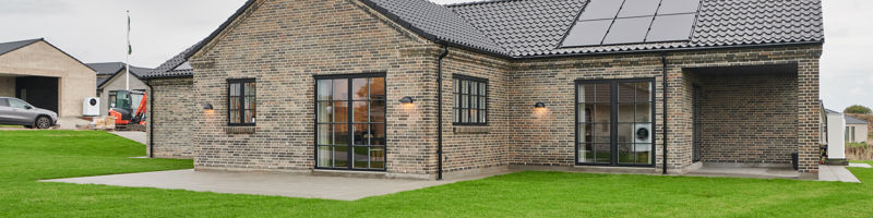 Drømmehus fra eurodan-huse med rustikke mursten, sort tegltag, solceller og overdækket terrasse.
