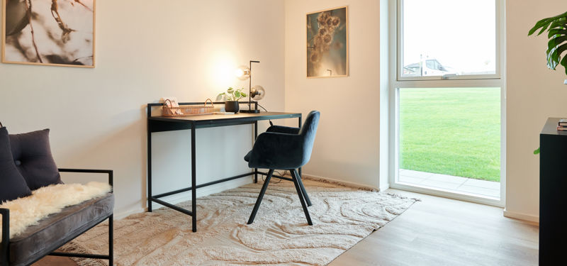 Hyggeligt hjemmekontor i nybyggeri med skrivebord, stort vindue og moderne indretning – inspiration til funktionelle husdrømme.