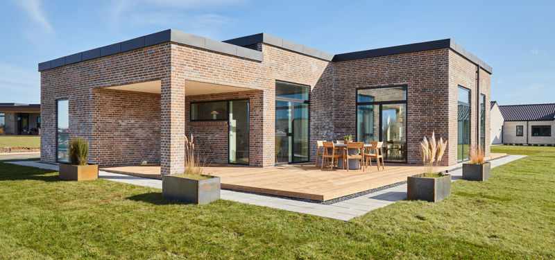 Udvendig facade med terasse i træ samt blomsterkummer i pladejern