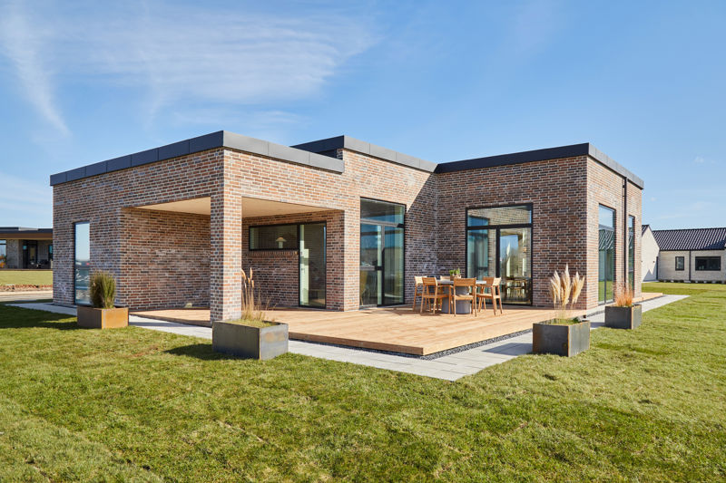 Udvendig facade med terasse i træ samt blomsterkummer i pladejern