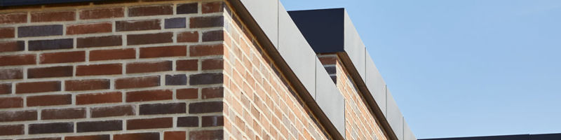 Detalje af moderne murstenshus med fladt tag og sorte sternkanter – stilrent nybyggeri fra eurodan-huse.