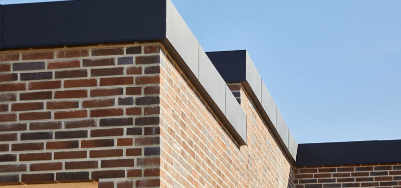 Detalje af moderne murstenshus med fladt tag og sorte sternkanter – stilrent nybyggeri fra eurodan-huse.