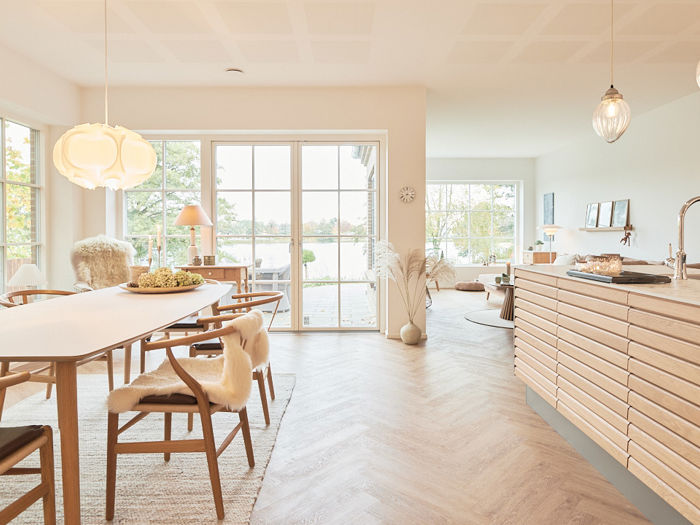 Lyst køkken-alrum i Maiken og Johnnys drømmehus med store vinduer og udsigt mod søen.