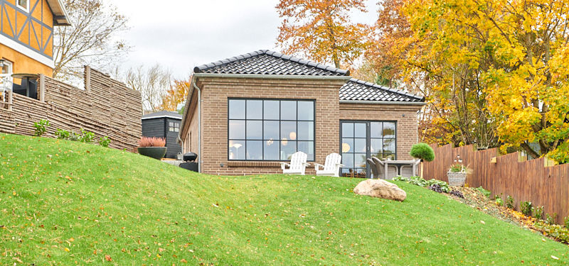 Maiken og Johnnys nybyggede murstenshus i Hornbæk med store vinduespartier og grøn have.