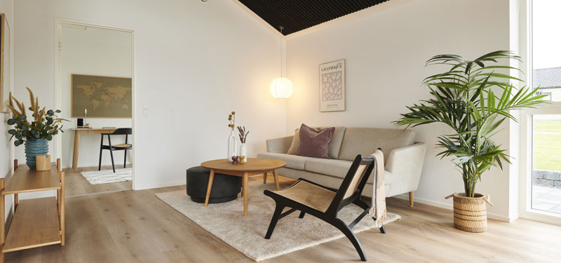 Lys og moderne stue i nybyggeri med loft til kip, sort akustikloft, store vinduespartier og stilren indretning – inspiration til personlige husdrømme.