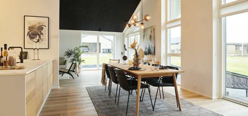 Lyst køkken-alrum i moderne nybyggeri med spiseplads, loft til kip, akustikloft og store gulv-til-loft-vinduer – inspiration til arkitektoniske husdrømme.