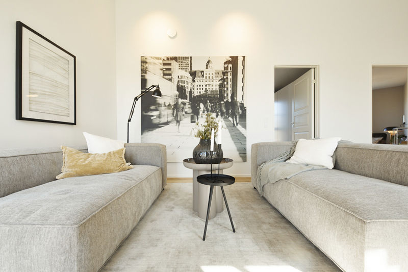 Sofagruppe fra eurodan-huse med to lysegrå sofaer overfor hinanden, rundt sidebord, sort læselampe, stort sort-hvidt billede og lyse vægge – inspiration til roligt opholdsrum, moderne nybyggeri og husdrømme.