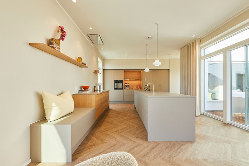 Moderne køkken i nybyg med grå fronter, trædetaljer, stor køkkenø, siddebænk og sildebensgulv – inspiration til køkkenet i drømmehuset.
