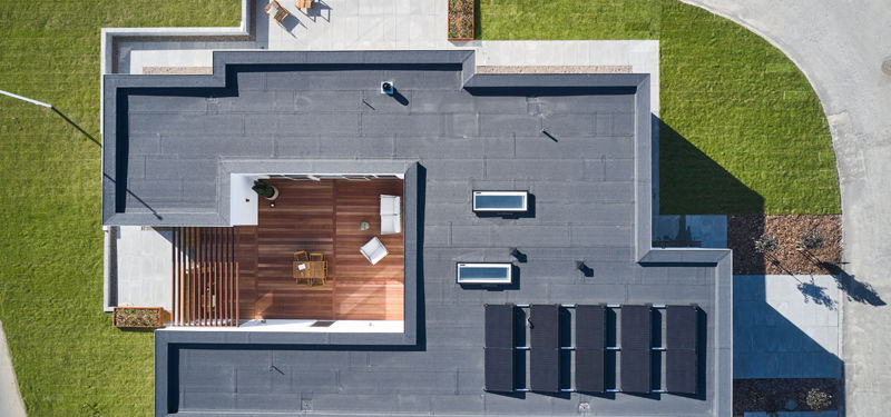Moderne nybyggeri fotograferet fra luften med fladt tag, ovenlysvinduer, solceller og integreret tagterrasse i træ – stilren inspiration til drømmehuset og moderne husdrømme.