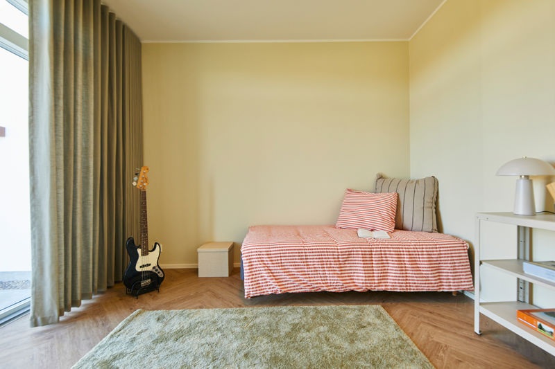 Børneværelse i moderne nybyg med stribet seng, guitar, lange gardiner og åben reol – inspiration til et personligt værelse i drømmehuset.