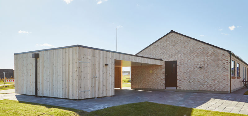 Fritstående carport og depotbygning med lodret lys træbeklædning, fladt tag, overdækket passagemellemrum og lys murstensfacade på huset – inspiration til carport, ekstra opbevaring og funktionelt nybyggeri fra eurodan-huse.