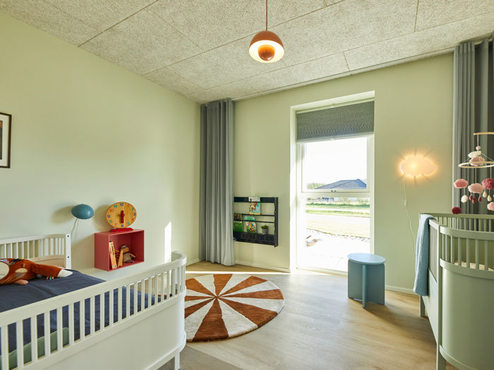 Lyst børneværelse i nybyggeri med tremmesenge, stort vindue, gardiner og moderne indretning – inspiration til familiens husdrømme.