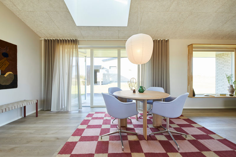 Lyst spiseområde i nybyggeri med rundt spisebord, ovenlys, store vinduespartier og indbygget siddevindue – inspiration til moderne husdrømme.