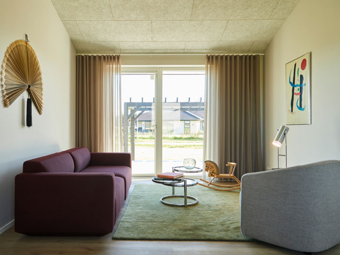 Hyggelig stue i moderne længehus med store vinduespartier, terrasseudgang og stilren indretning – inspiration til lyse rum i et nyt hus.