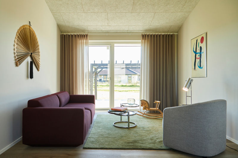 Hyggelig stue i moderne længehus med store vinduespartier, terrasseudgang og stilren indretning – inspiration til lyse rum i et nyt hus.