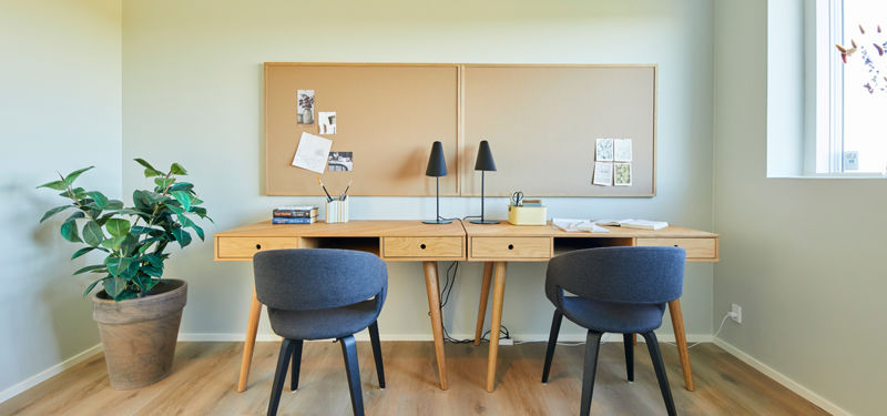 Kontor i moderne nybygget hjem med to arbejdspladser, opslagstavler og naturligt lys – funktionelt husbyggeri til hverdagen