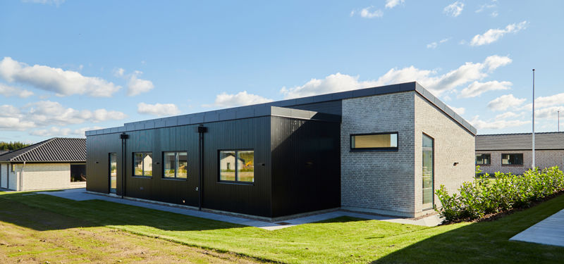 Moderne længehus med sort træbeklædning, lyse mursten og minimalistisk facade – arkitektonisk inspiration til nybyggeri med eurodan-huse