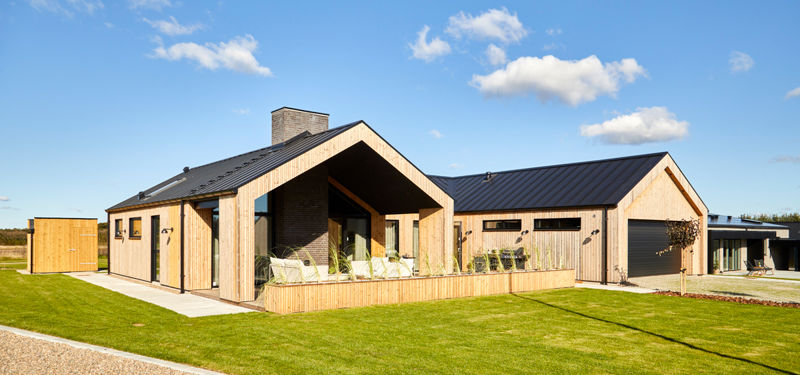 Nybyggeri i barnhouse-stil fra eurodan-huse med træbeklædt facade, sort tag, stor overdækket terrasse og integreret dobbeltgarage