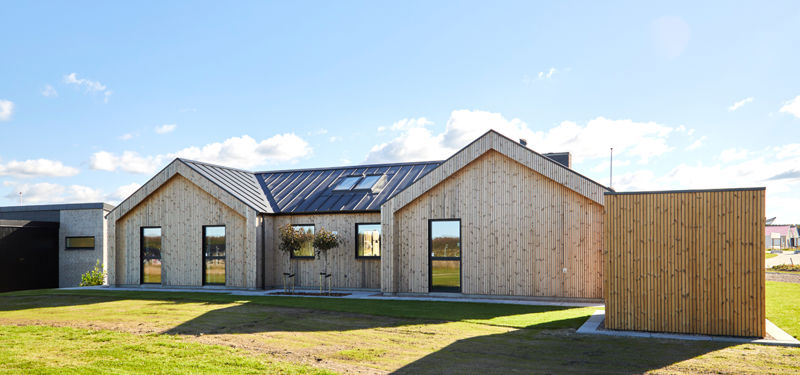 Nybygget barnhouse med lodret træfacade, sort tag, store vinduer og enkel arkitektur der viser moderne husbyggeri med rustikt udtryk