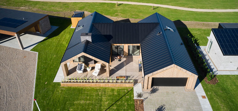 Barnhouse fra eurodan-huse med sort tag, træbeklædning, integreret garage og terrasse som samler hus og have