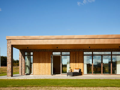 Moderne udstillingshus fra eurodan-huse med træfacade, murstenssøjler, overdækket terrasse og store vinduespartier til arkitektonisk nybyggeri og husbyggeri.