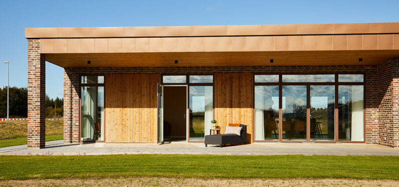 Moderne udstillingshus fra eurodan-huse med træfacade, murstenssøjler, overdækket terrasse og store vinduespartier til arkitektonisk nybyggeri og husbyggeri.