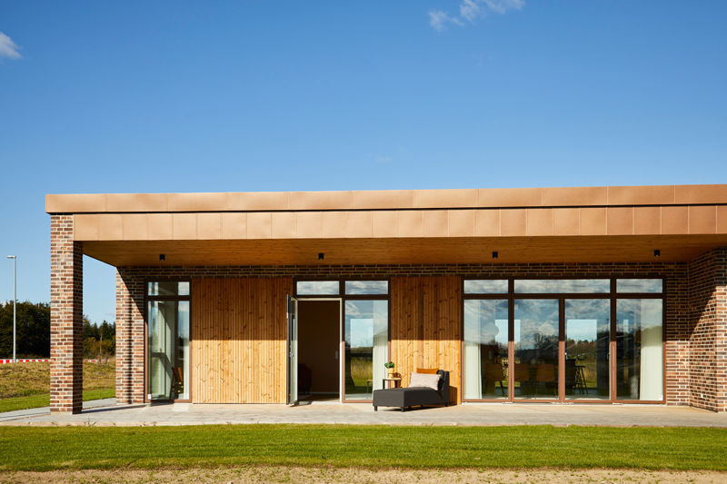 Moderne udstillingshus fra eurodan-huse med træfacade, murstenssøjler, overdækket terrasse og store vinduespartier til arkitektonisk nybyggeri og husbyggeri.