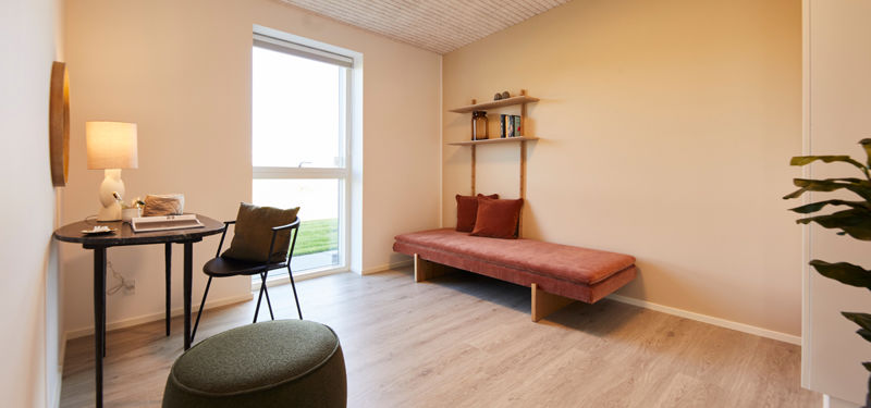 Fleksibelt værelse i udstillingshus fra eurodan-huse med daybed, skrivebord, træloft og stort vindue til inspiration for nybyggeri og husbyggeri.