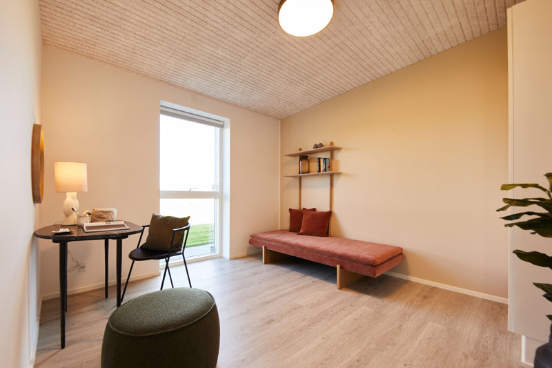 Fleksibelt værelse i udstillingshus fra eurodan-huse med daybed, skrivebord, træloft og stort vindue til inspiration for nybyggeri og husbyggeri.