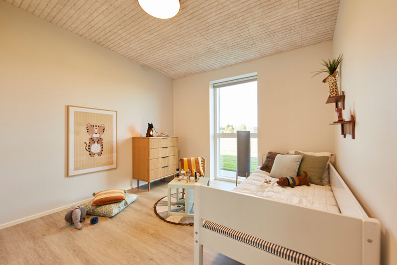 Børneværelse i udstillingshus fra eurodan-huse med børneseng, legeområde, træloft, kommode og stort lysindfald til moderne nybyggeri og familievenligt husbyggeri.