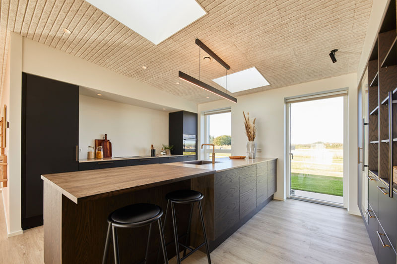 Moderne køkken i udstillingshus fra eurodan-huse med stor køkkenø, mørke fronter, træloft, ovenlys og terrassedør til inspiration for nybyggeri og husbyggeri.