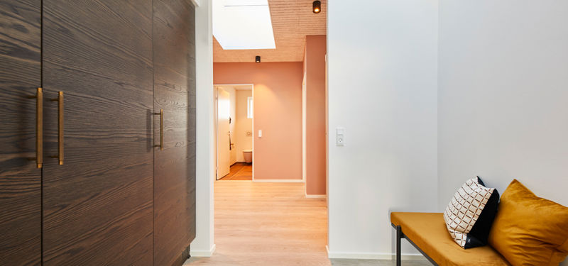 Entré i udstillingshus fra eurodan-huse med mørke træskabe, siddebænk, ovenlys og varm vægfarve til moderne nybyggeri og husbyggeri.