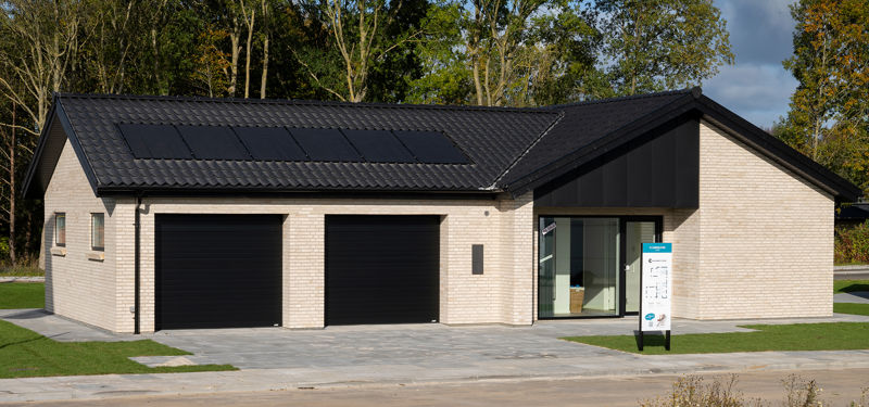 Garagefacade med to sorte garageporte, lyse mursten, sort tag, store tagflader med solceller og indgangsparti ved siden af – inspiration til dobbelt garage, nybyggeri og funktionelt husbyggeri fra eurodan-huse.
