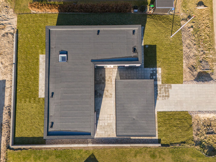 Nybyggeri set fra oven med fladt tag, mørk carport, tagvindue og minimalistisk arkitektur