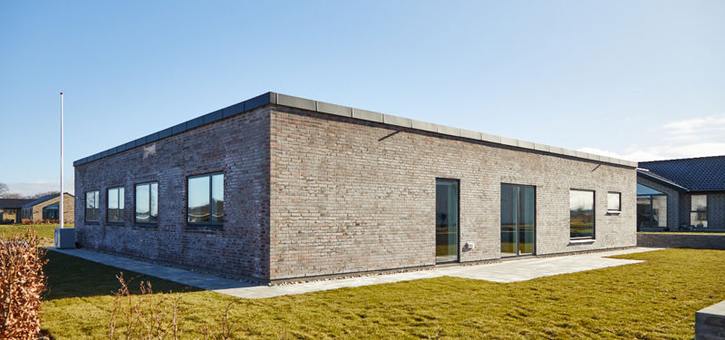 Moderne nybyggeri med fladt tag, murstensfacade, store vinduer og have omkring huset