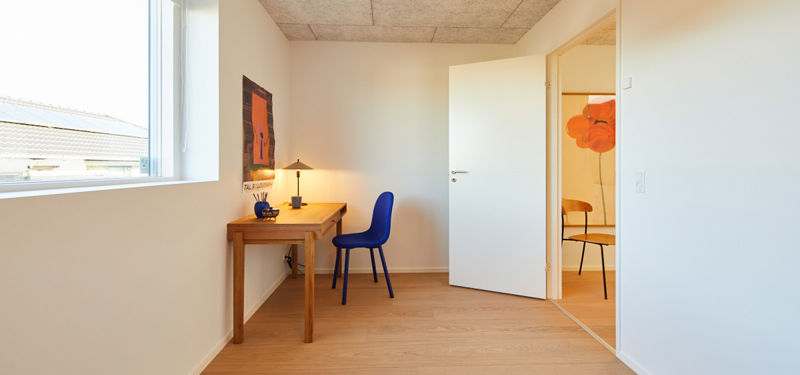 Kontor i moderne nybyggeri med skrivebord, stort vindue og fleksibel indretning