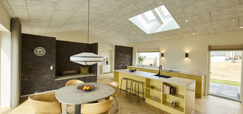 Spiseplads i køkken-alrum fra eurodan-huse med dækket bord, moderne stole, pendel over bordet, lyse vægge og åben forbindelse til køkkenet – inspiration til nybyggeri og husdrømme.