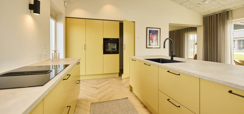 Åbent køkken-alrum fra eurodan-huse med spiseplads, køkkenzone, store vinduer, dagslys og harmonisk indretning – inspiration til moderne husbyggeri og nybyggerdrømme.
