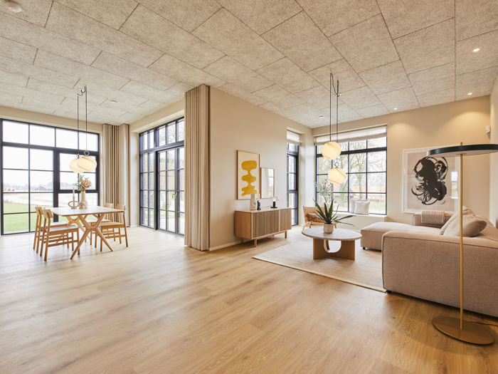 Lyst opholdsrum i moderne vinkelhus med spiseplads, beige sofa, store gulv-til-loft-vinduer og lange gardiner – inspiration til indretning og nye husdrømme.
